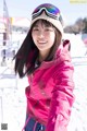 A young woman in a pink jacket and ski goggles.