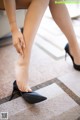 A woman in black high heels is putting on her shoes.