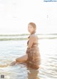 A woman sitting in the water on a beach.