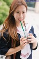 A young woman in a school uniform holding a drink.