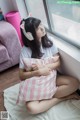 A woman sitting on a bed with a pillow and headphones on.