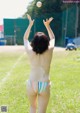 A woman in a bikini throwing a baseball in the air.