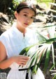 A woman in a white dress holding a palm leaf.