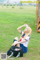 A woman sitting on the grass drinking water from a bottle.