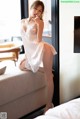 A woman in a white lingerie sitting on a couch.