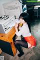 A woman sitting at a desk in front of a printer.