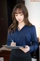 A woman in a blue shirt and black skirt holding a tablet.