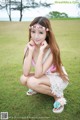 A woman in a pink bikini sitting on the grass.