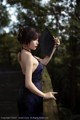 A woman in a blue dress holding a black fan.