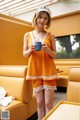 A woman in a yellow top and shorts holding a cup of coffee.