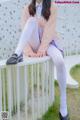 A woman sitting on top of a white bench.