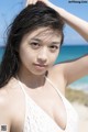 A woman in a white bikini posing on the beach.