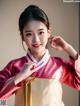 A woman in a red and gold hanbok poses for a picture.