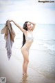 A woman in a white bikini standing on a beach.