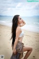 A woman in a white bikini sitting on a beach.