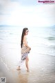 A woman walking on the beach in a white bikini.