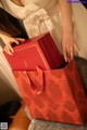 A woman in a white dress holding a red gift bag.