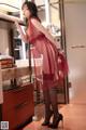 A woman in a red dress standing in a bathroom.