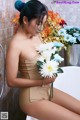 A woman sitting in a bathtub holding a bunch of flowers.